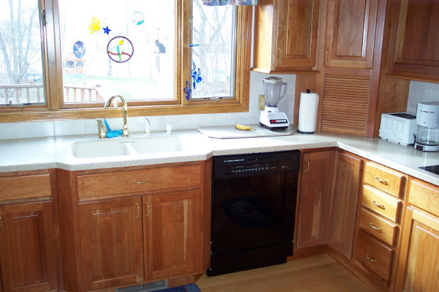 Cherry base cabinets and a solid surface countertop running to the sink
