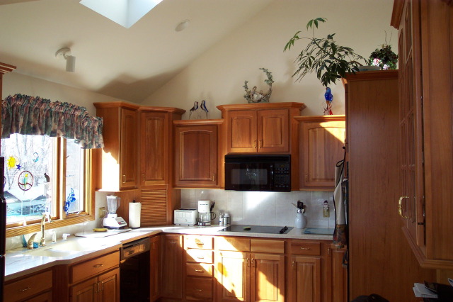 Cherry kitchen under a vaulted ceiling with a skylight and a glazed corner cabinet