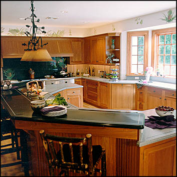 Kitchen with a dark stone island top, raised panel cabinetry and a wrought iron chandelier